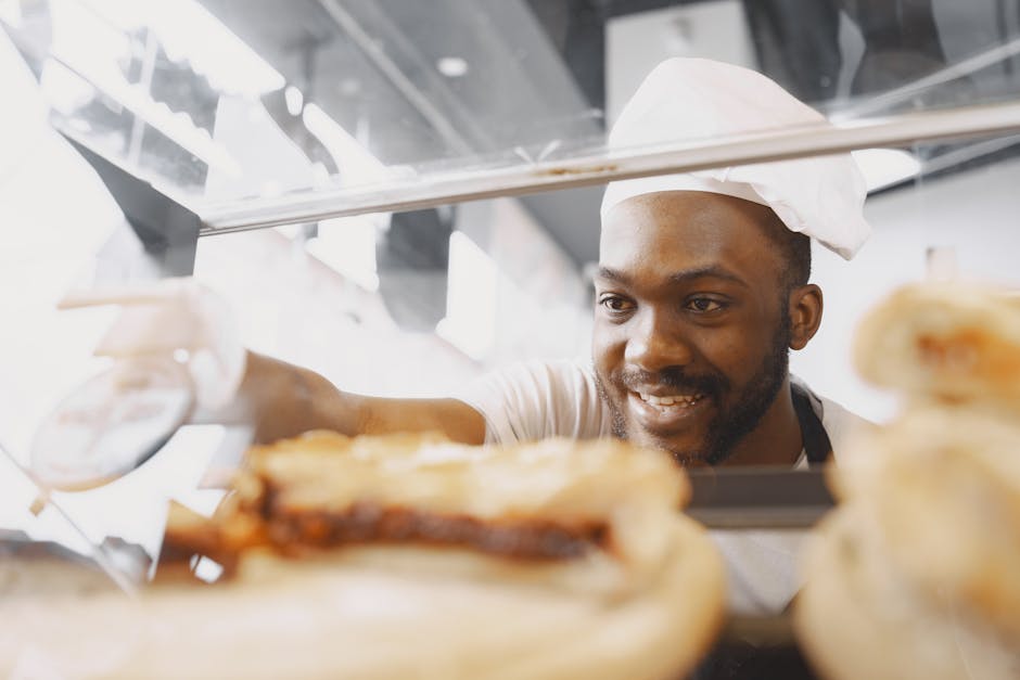 A cheerful baker arranges fresh bread in an indoor bakery display case, reflecting culinary passion.