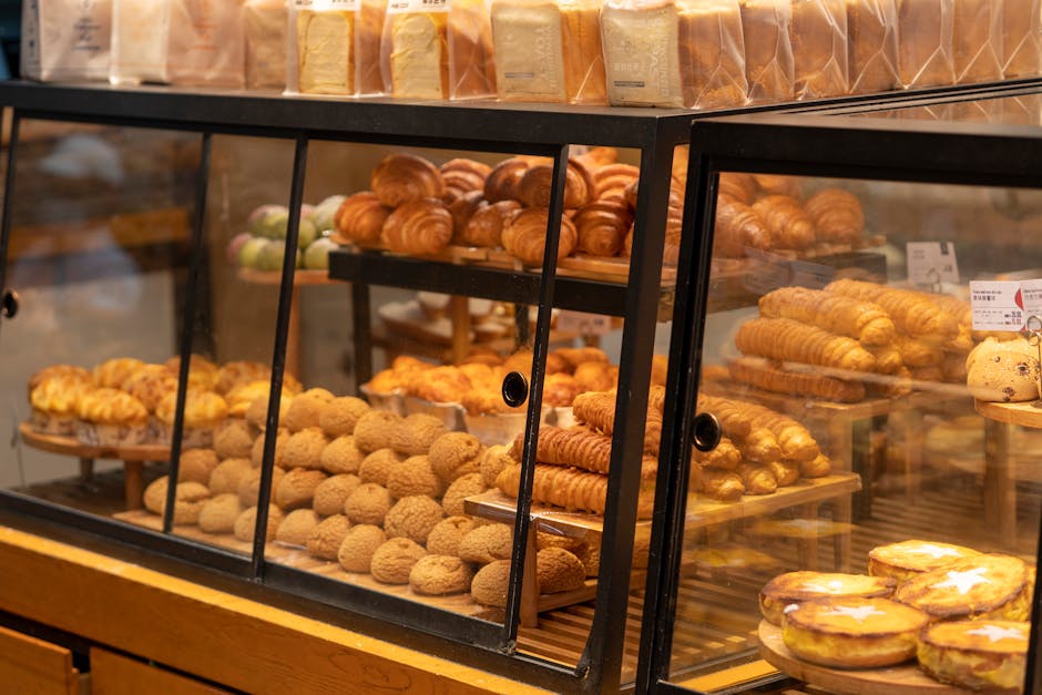 A display case filled with assorted pastries and breads in a bakery setting, showcasing fresh baked goods.