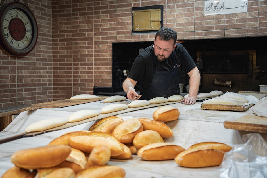 Skilled baker meticulously shaping dough for freshly baked artisan bread in a traditional bakery setting.
