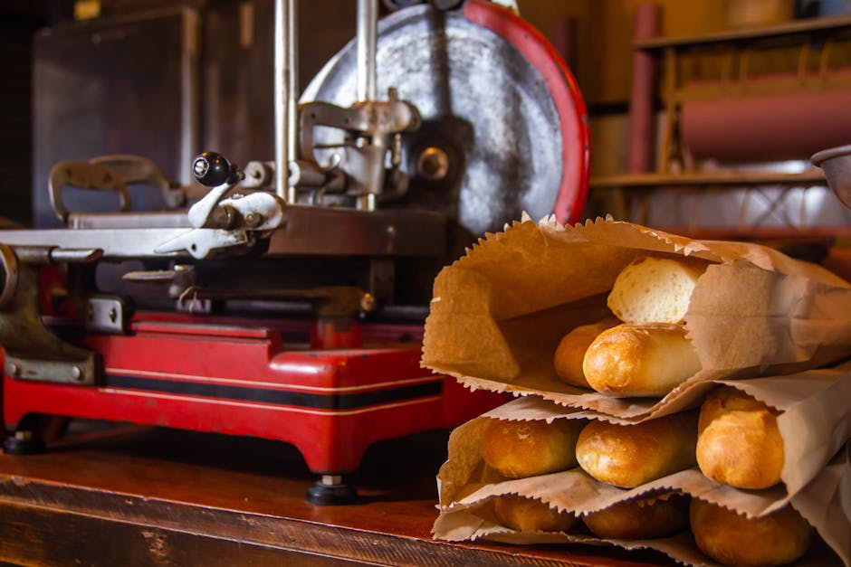 Warm bakery scene featuring fresh baguettes in paper bags beside a vintage slicer.