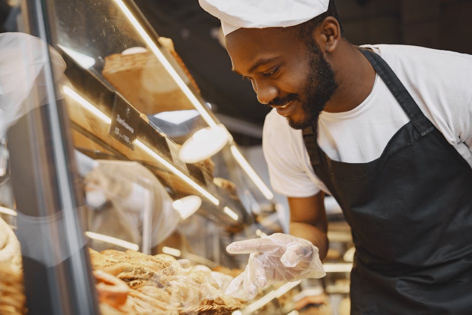 A cheerful baker in a bakery showcases fresh pastries behind a glass display case.